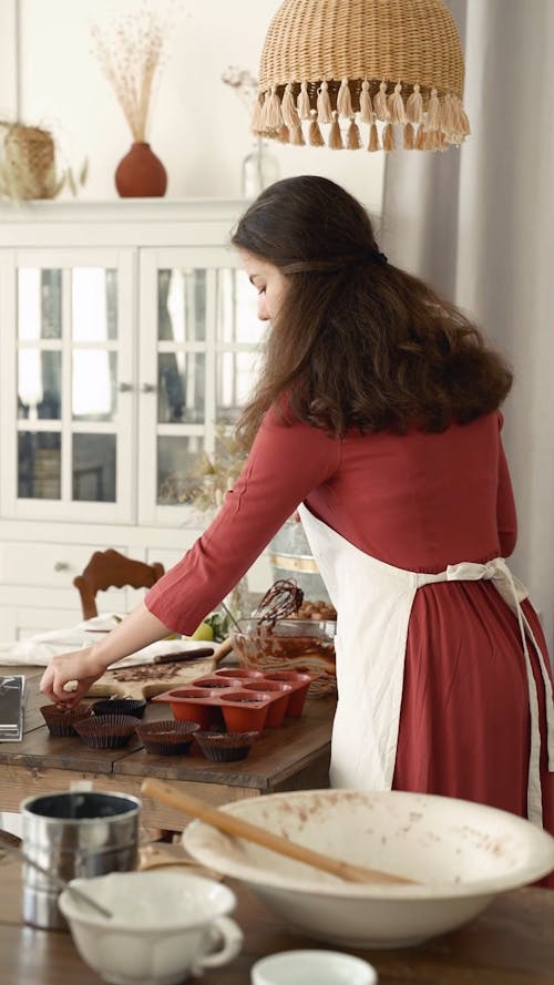 A Woman Filling A Cupcakes Tray