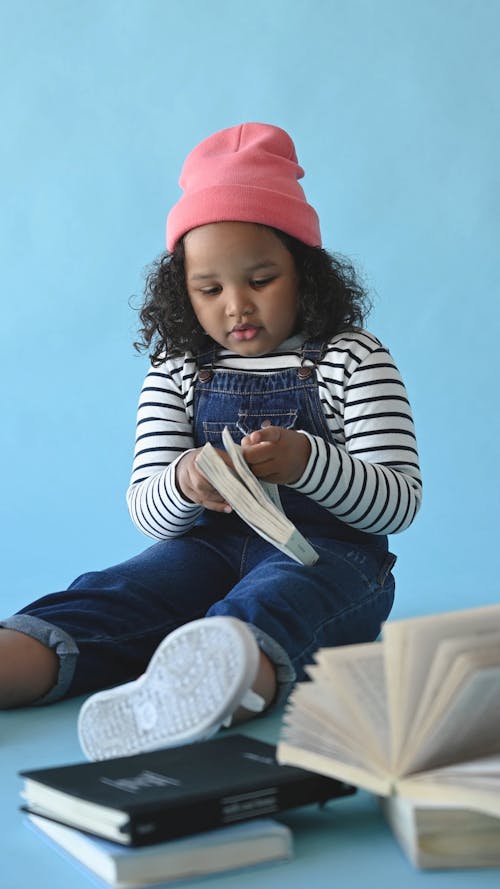 A Young Girl Reading Books Sitting On The Floor