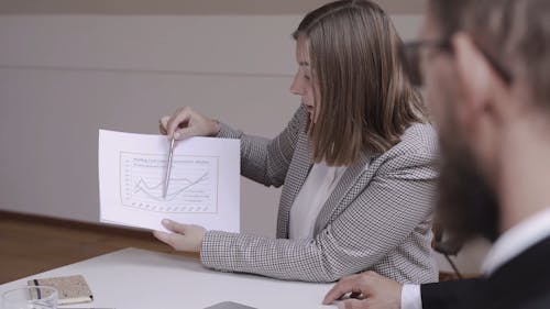 A Woman Explaining A Chart To Associates
