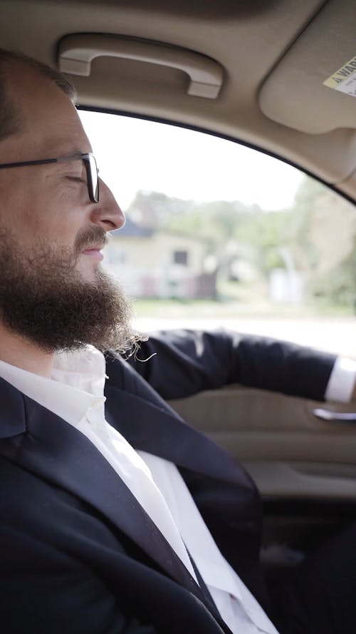 A Bearded Man Driving A Car