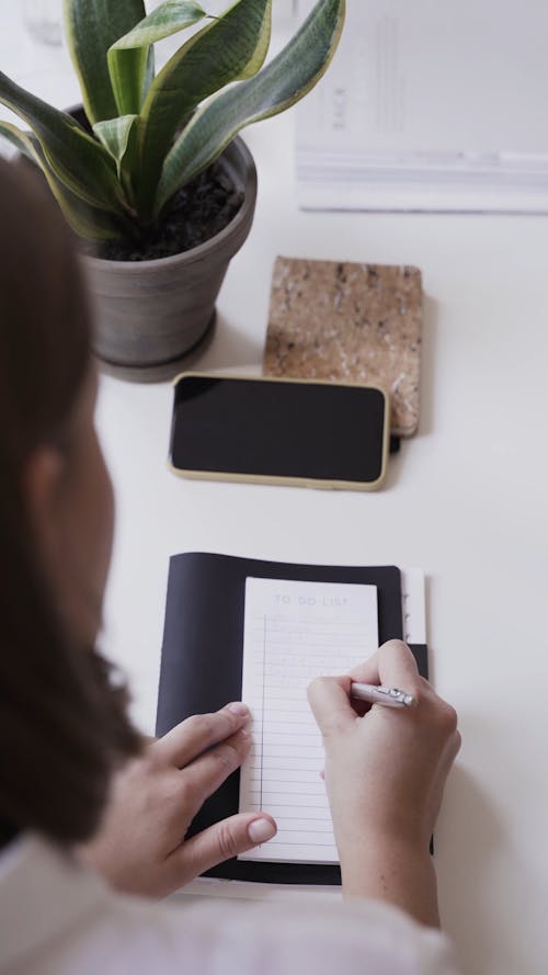 A Woman Writing On A Piece Of Paper