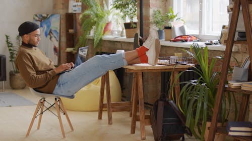 A Young Man Sitting Comfortably While Typing On His Laptop