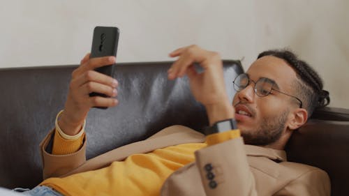 A Man Talking On His Phone While Lying Down In The Sofa