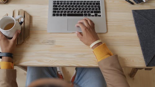 A Man Drinking Tea While Working On A Laptop