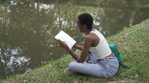 一個女人坐在草地上，一邊讀她的筆記
