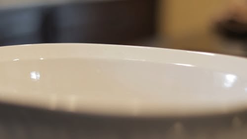 Close-Up View of a Person Adding a Liquid into a Bowl