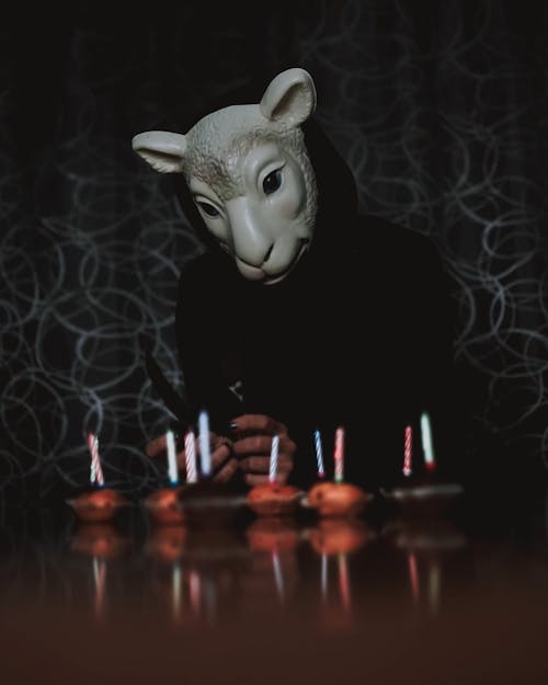 A Person Wearing a Mask Playing with Candles on Cupcakes