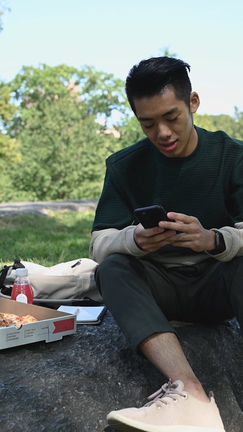 A Man Smiling while Using His Smartphone