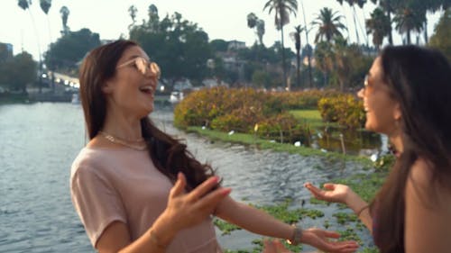 Female Friends Hugging and Talking by a Lake