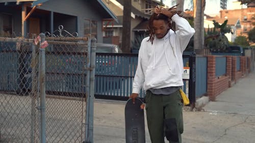 Man Walking and Holding a Skateboard