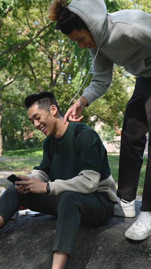 Smiling Young Men Chatting and Using Smartphone 