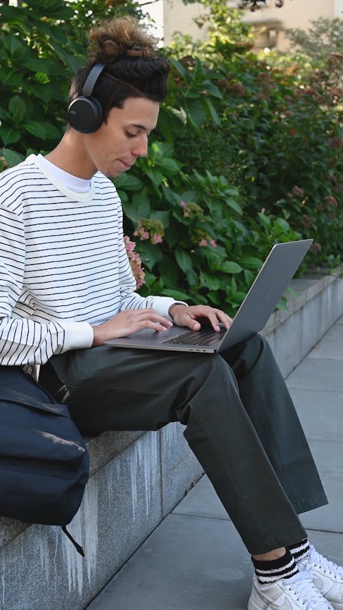 A Man Using His Laptop while Listening to Music