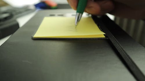 A Person Writing on a Sticky Note