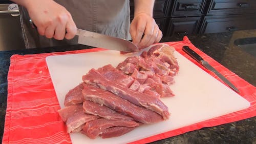 A Person Slicing a Raw Meat Using a Knife