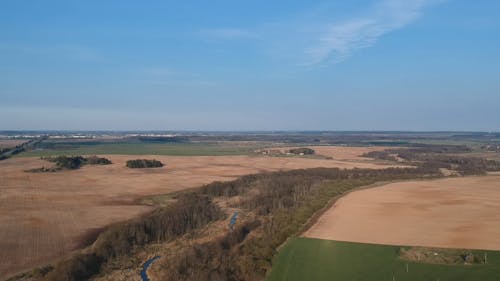 Drone Footage of Vast Agricultural Land Under Blue Sky