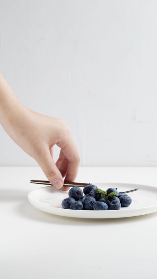 A Person Getting a Piece of Blueberry by Using a Fork