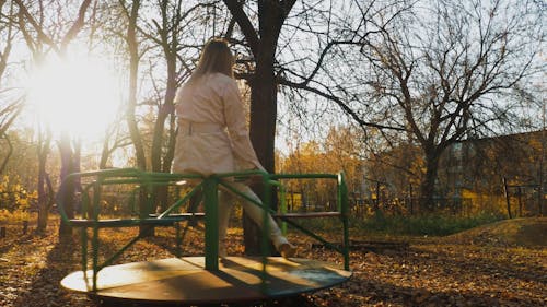 A Woman Ridding A Merry Go Round In A Playground