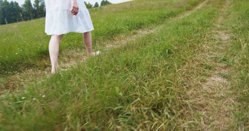 Young Woman Walking in Grass Field 