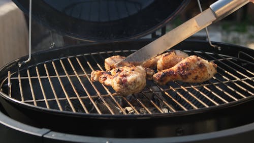 Person Cooking Chicken on a Grill