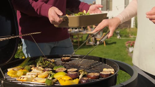 Person Putting Grilled Vegetables on a Tray