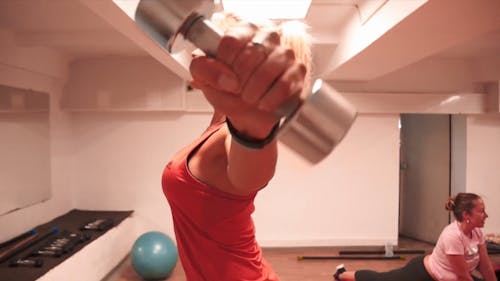 A Woman Holding a Dumbbell While Rotating Her Arm