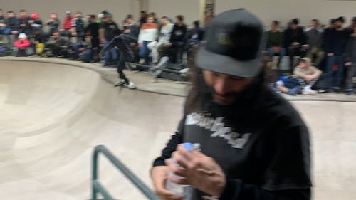 Group of People Watching a Man Roller Skating in Skate Bowl