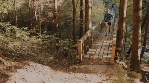 A Man Walking on a Wooden Footbridge