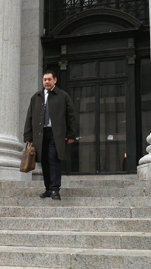 Man with Corporate Bag and Attire Coming Out of a Building