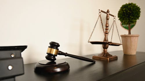 Balance Scales and Gavel Placed on a Wooden Desk