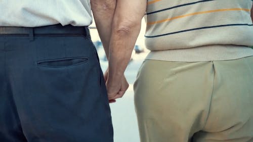 A Couple Holding Each Other's Hand While Walking