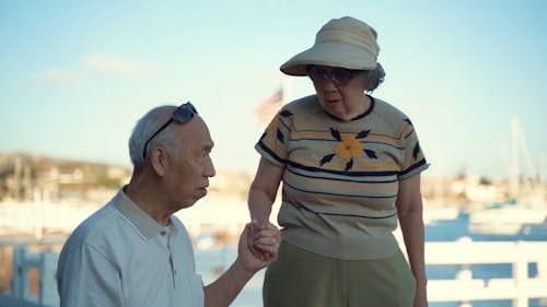 An Elderly Man Guiding His Partner In Walking