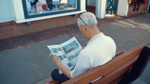 Elderly Man Sitting on the Bench Reading Newspaper
