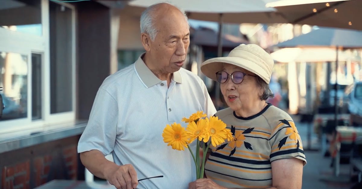 Elderly Couple Standing on the Street Side Holding Yellow Flowers Free ...