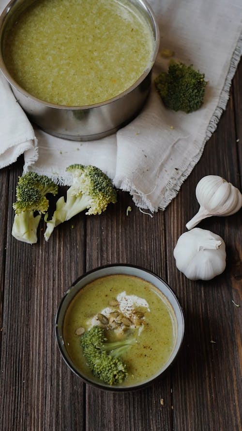 A Person Stirring a Broccoli Soup Using a Spoon