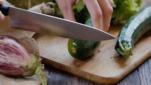 Close-Up View of Person Cutting Zucchini With a Knife