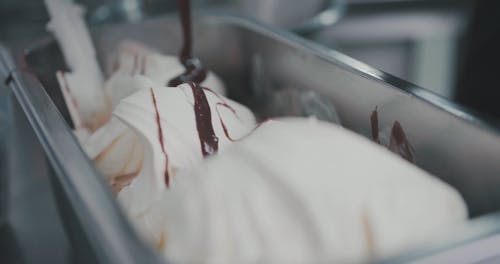Close-Up View of Person Drizzling Chocolate Syrup on Ice Cream