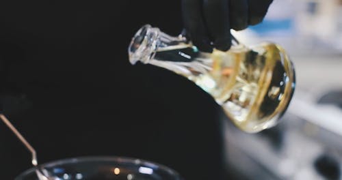 A Person Pouring Oil to the Glass Bowl