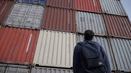 Man Looking at the Huge Shipping Containers