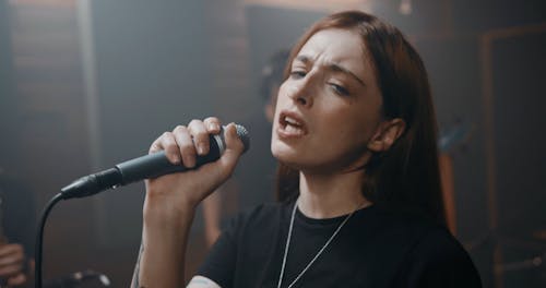 A Woman Emotionally Singing With Her Music Band