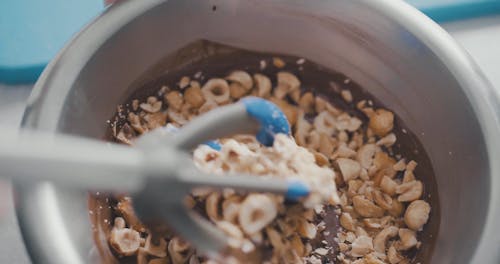 Person Mixing a Nuts on the Melted Chocolate