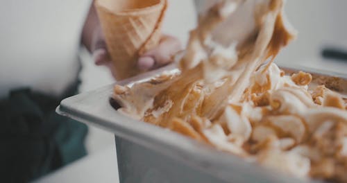 A Person Putting Scoop of Ice Cream in a Cone