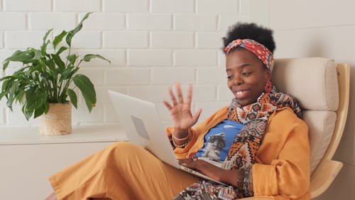 A Woman Sitting on an Armchair While Having a Video Conference through Her Laptop