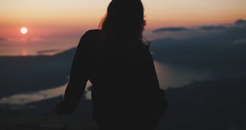 A Woman Enjoying The Sunset View From The Mountain Top