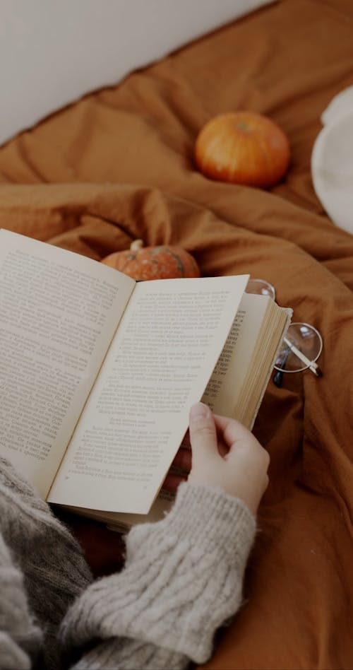 A Person Reading A Book In Bed