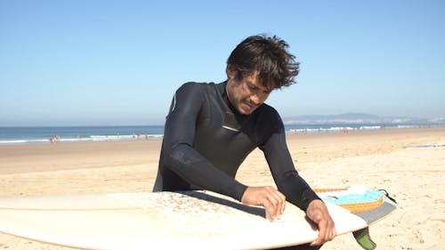 Surfer Waxing Surfboard