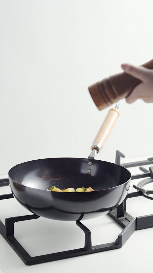 A Person Using a Wooden Pepper Mill