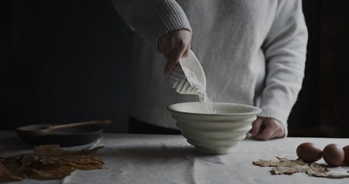 Person Pouring Flour on a Bowl