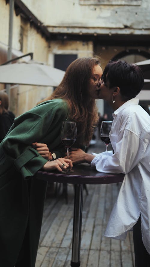 Two Girls with Wine Kissing in a Bar 