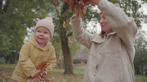Mother and Child Throwing Autumn Leaves In the Air