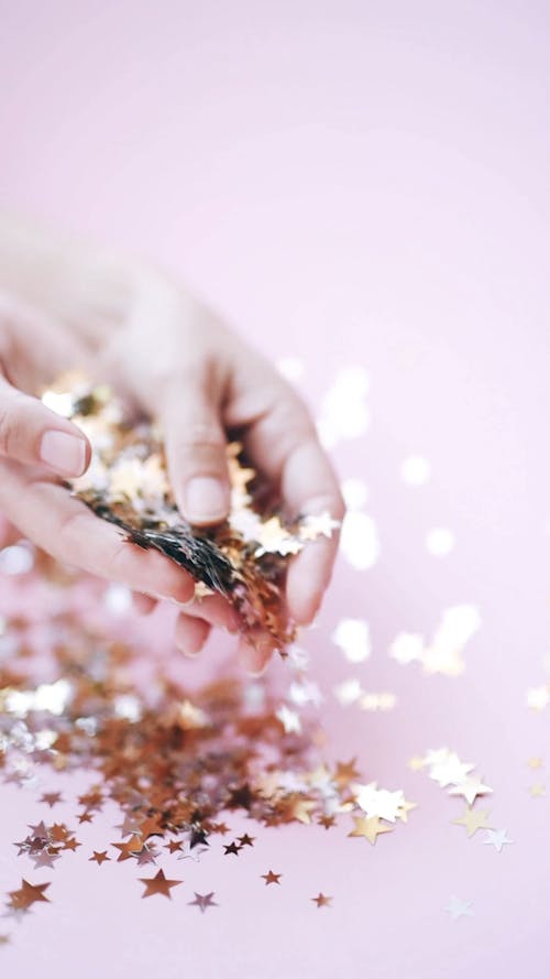 Close-Up View of a Person Holding Tiny Golden Stars
